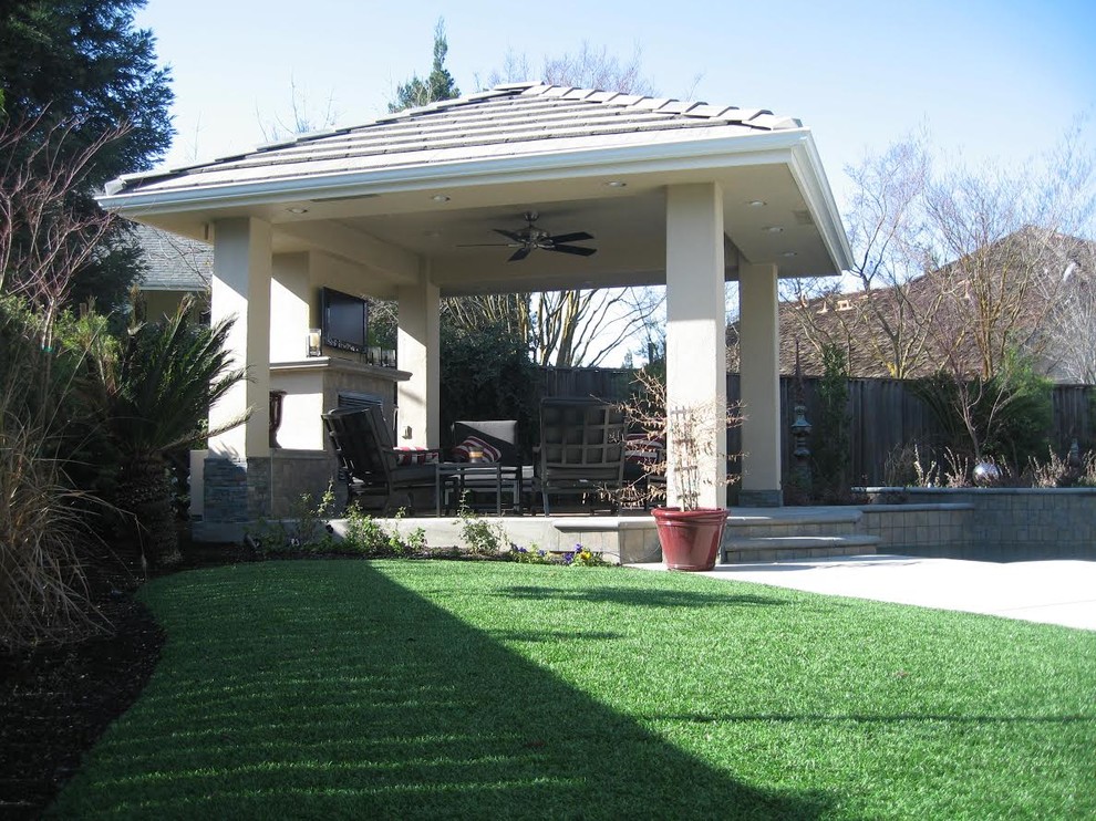 Idées déco pour une grande terrasse arrière classique avec un foyer extérieur, un gazebo ou pavillon et des pavés en béton.