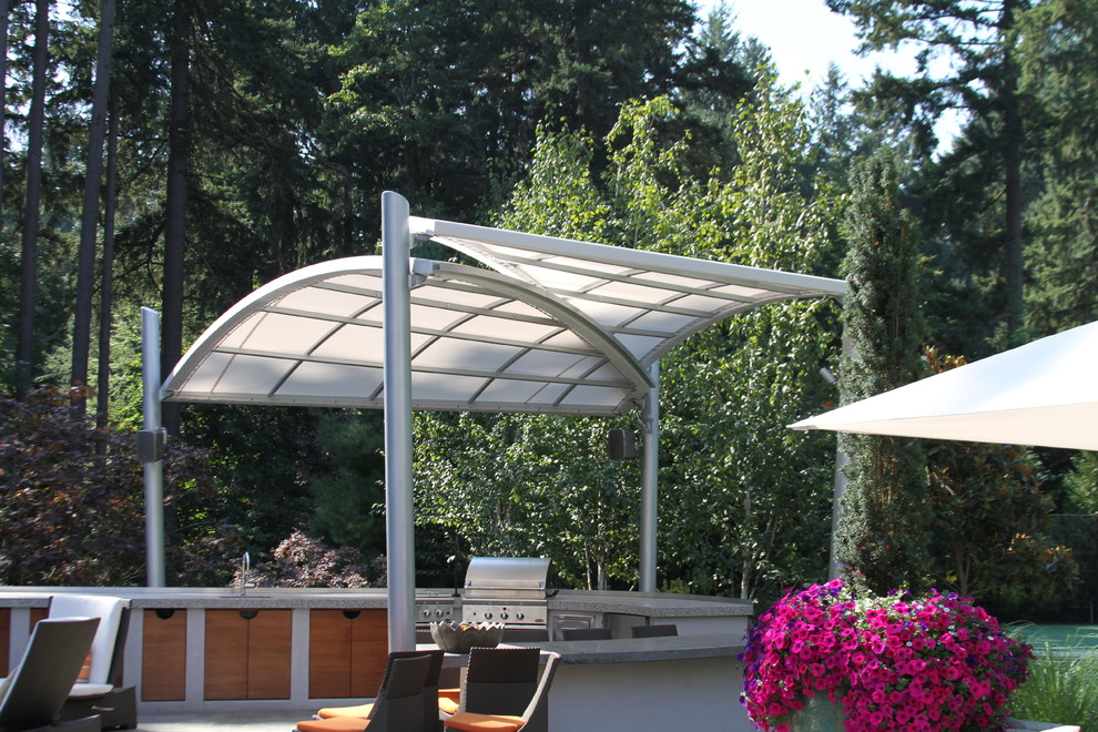 Modelo de patio actual grande en patio trasero con cocina exterior, adoquines de hormigón y toldo