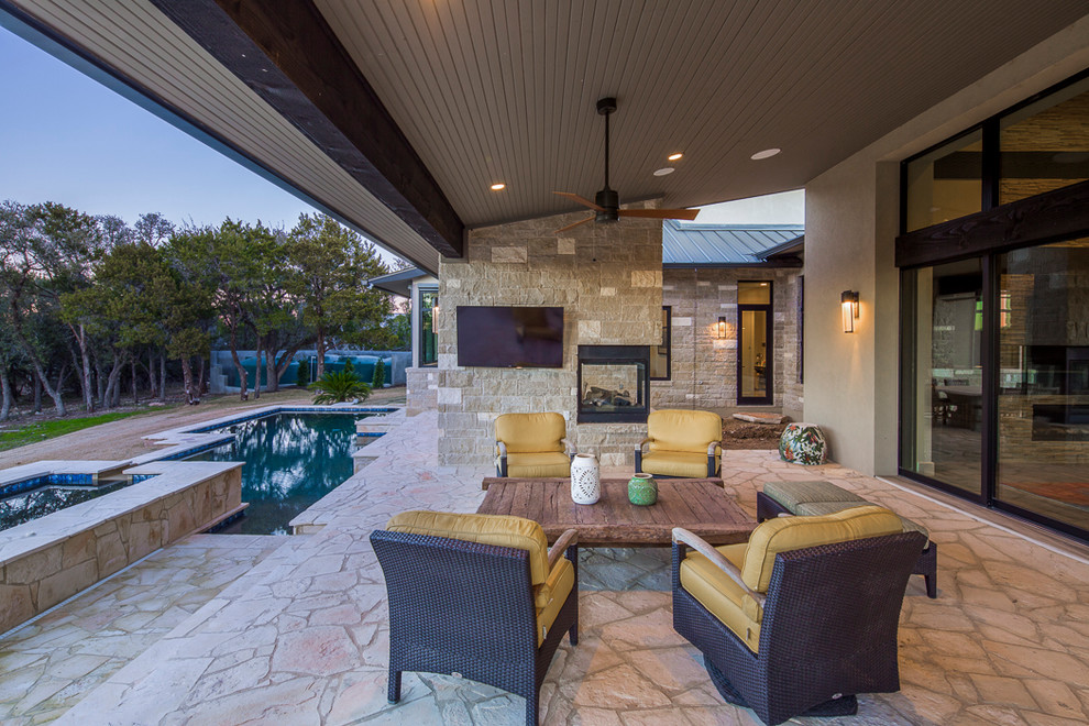 Inspiration for a huge contemporary backyard stone patio remodel in Austin with a fireplace and a roof extension