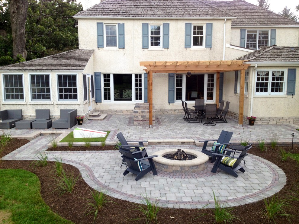 Design ideas for a large traditional back patio in Chicago with a fire feature, brick paving and a pergola.