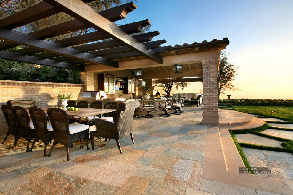 Large elegant backyard brick patio kitchen photo in Orange County with a pergola