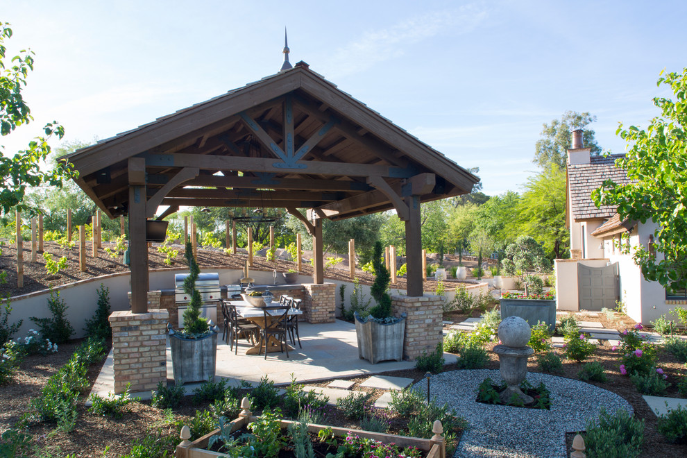 This is an example of a large traditional back patio in Phoenix with an outdoor kitchen, concrete paving and a gazebo.