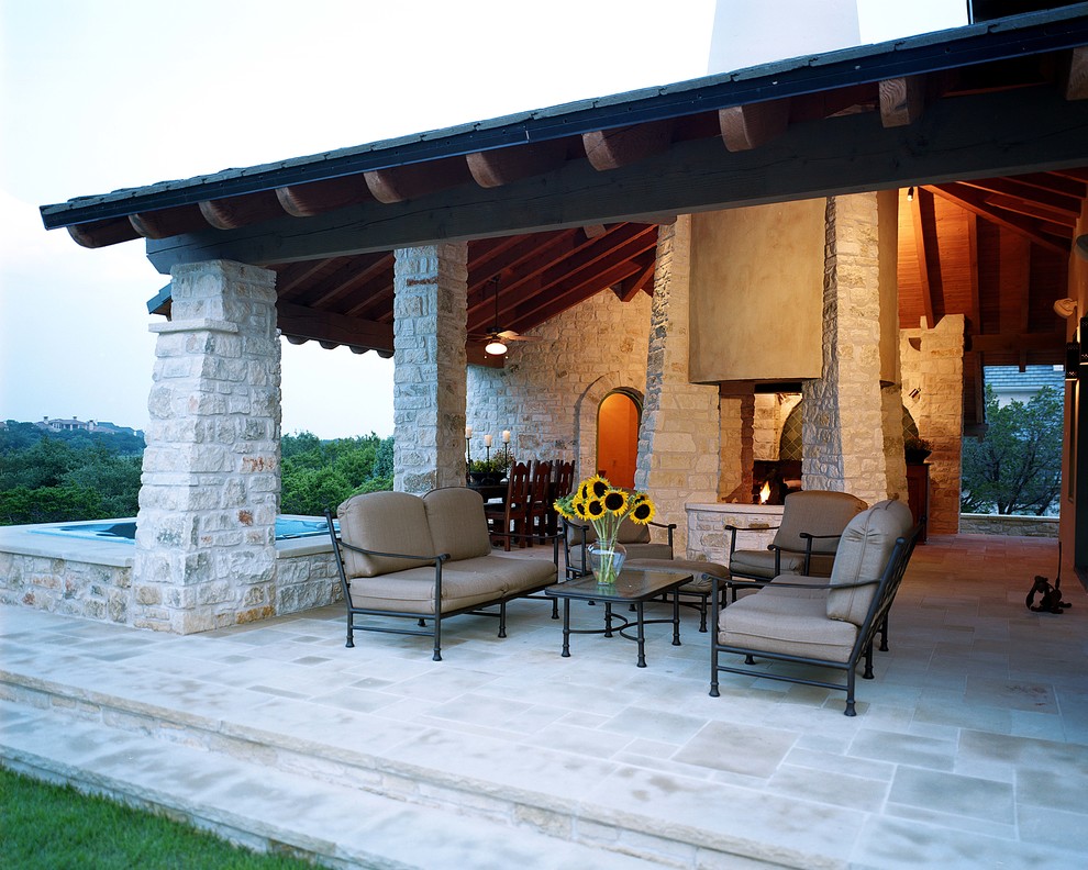 Idee per un grande patio o portico tradizionale dietro casa con un focolare, pavimentazioni in pietra naturale e un tetto a sbalzo