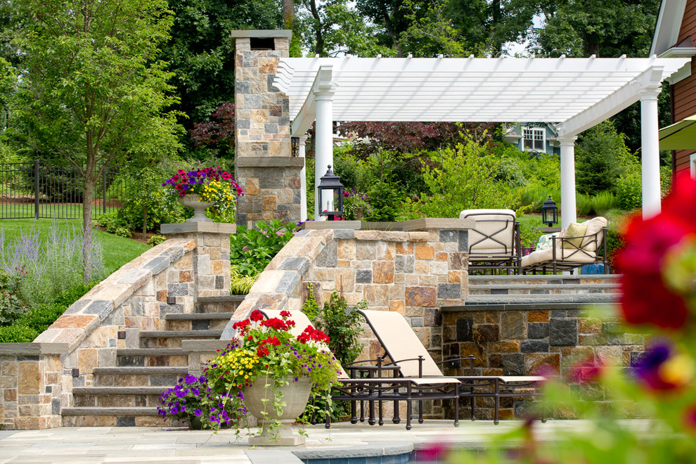 Foto de patio clásico grande en patio trasero con brasero, adoquines de piedra natural y pérgola