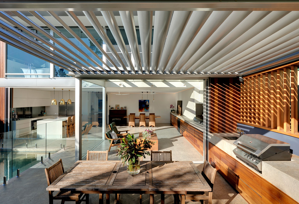 Imagen de patio contemporáneo grande en patio trasero con cocina exterior, losas de hormigón y toldo