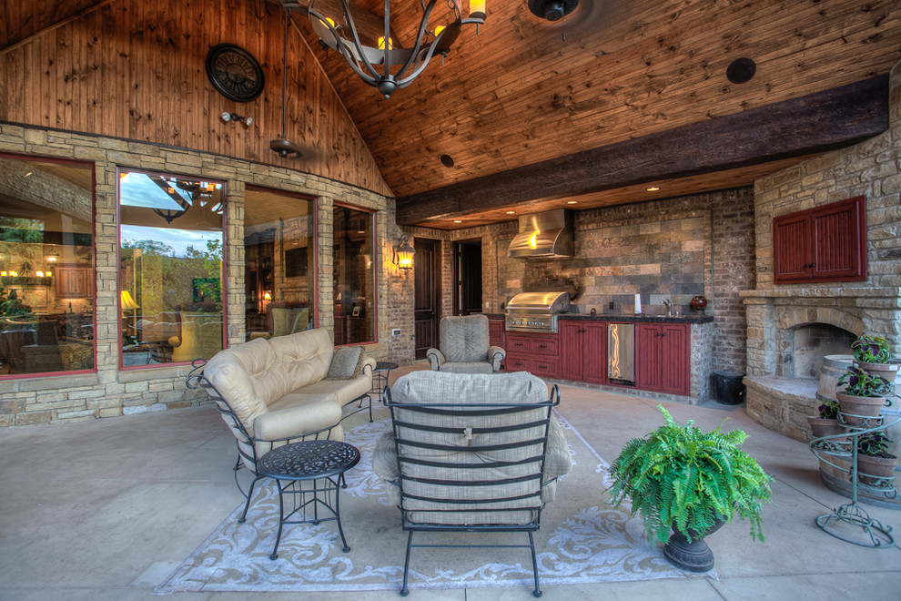 This is an example of a large rustic back patio in Oklahoma City with concrete slabs, a roof extension and a bbq area.