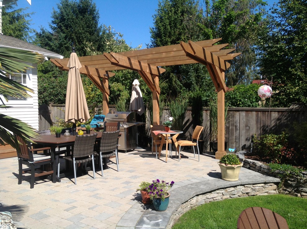 Example of a mid-sized classic backyard stone patio kitchen design in Vancouver with no cover