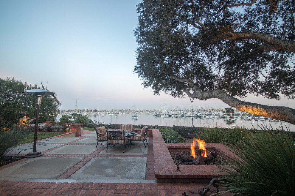 Großer Uriger Patio hinter dem Haus mit Feuerstelle und Pflastersteinen in San Diego