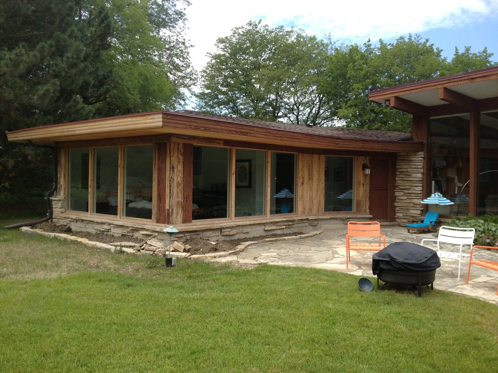 Inspiration pour une grande terrasse arrière vintage avec un foyer extérieur, des pavés en pierre naturelle et une extension de toiture.