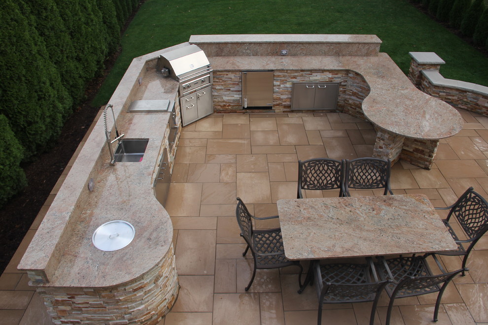 Imagen de patio moderno de tamaño medio sin cubierta en patio trasero con cocina exterior y adoquines de piedra natural