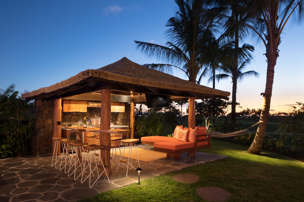 Bild på en mellanstor tropisk uteplats på baksidan av huset, med utekök, naturstensplattor och ett lusthus