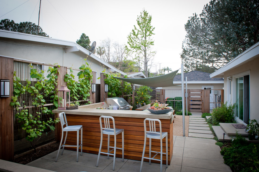 Large beach style back patio in Los Angeles with gravel, an outdoor kitchen and an awning.