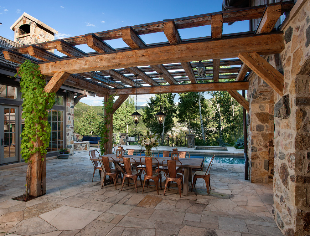 This is an example of a rustic patio in Denver with a pergola and natural stone paving.