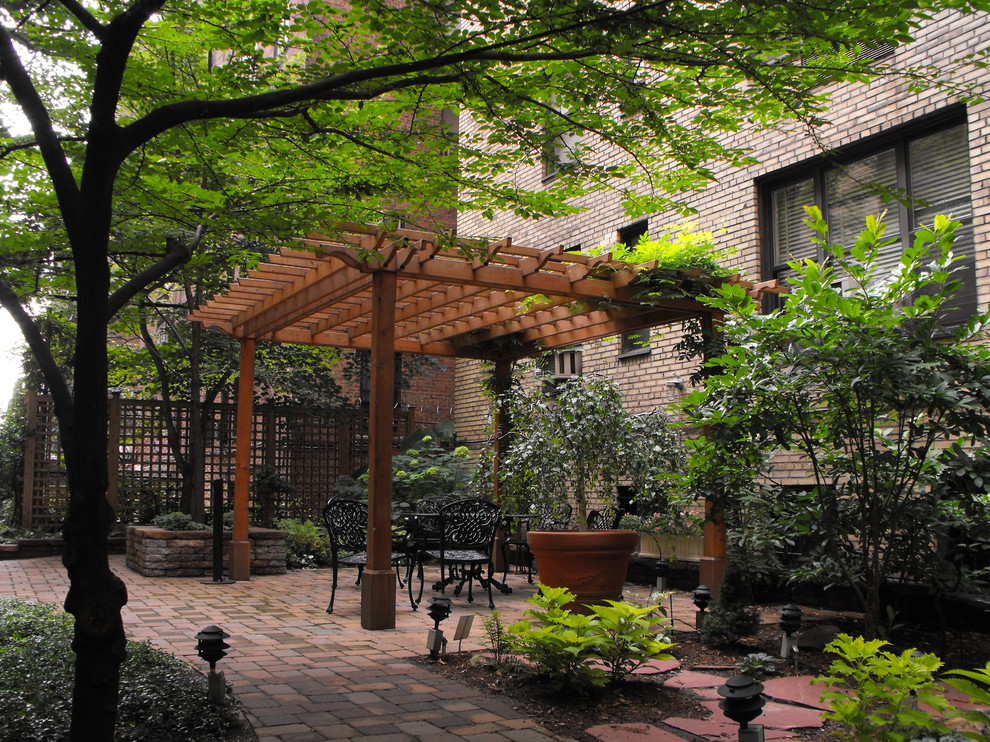 Diseño de patio clásico grande en patio trasero con adoquines de ladrillo y pérgola