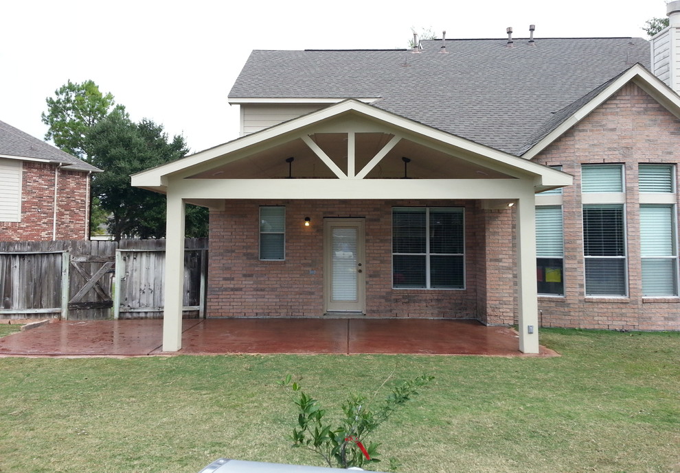 Foto di un patio o portico tradizionale dietro casa con lastre di cemento e un tetto a sbalzo