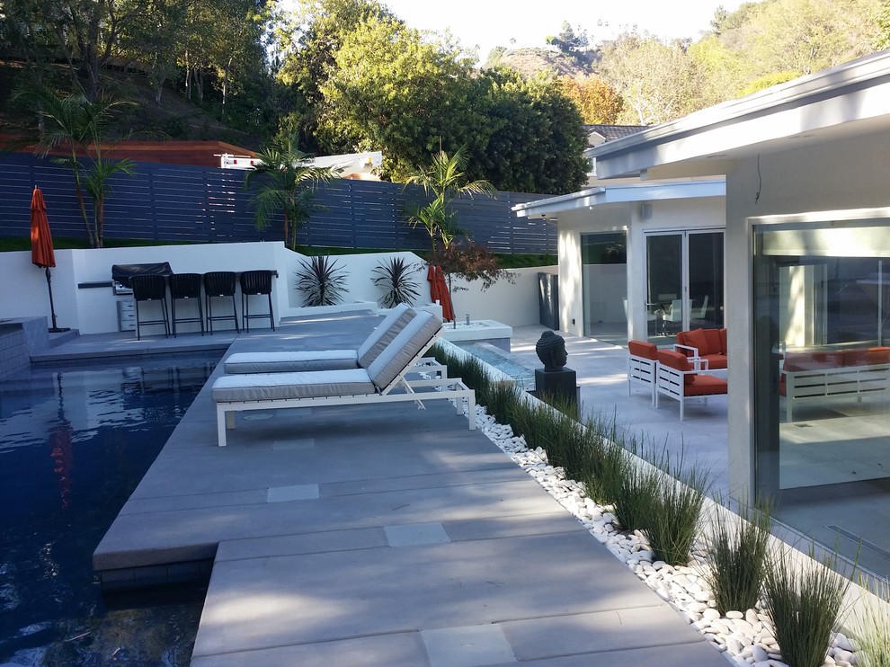 Large modern back patio in Los Angeles with a water feature, tiled flooring and no cover.