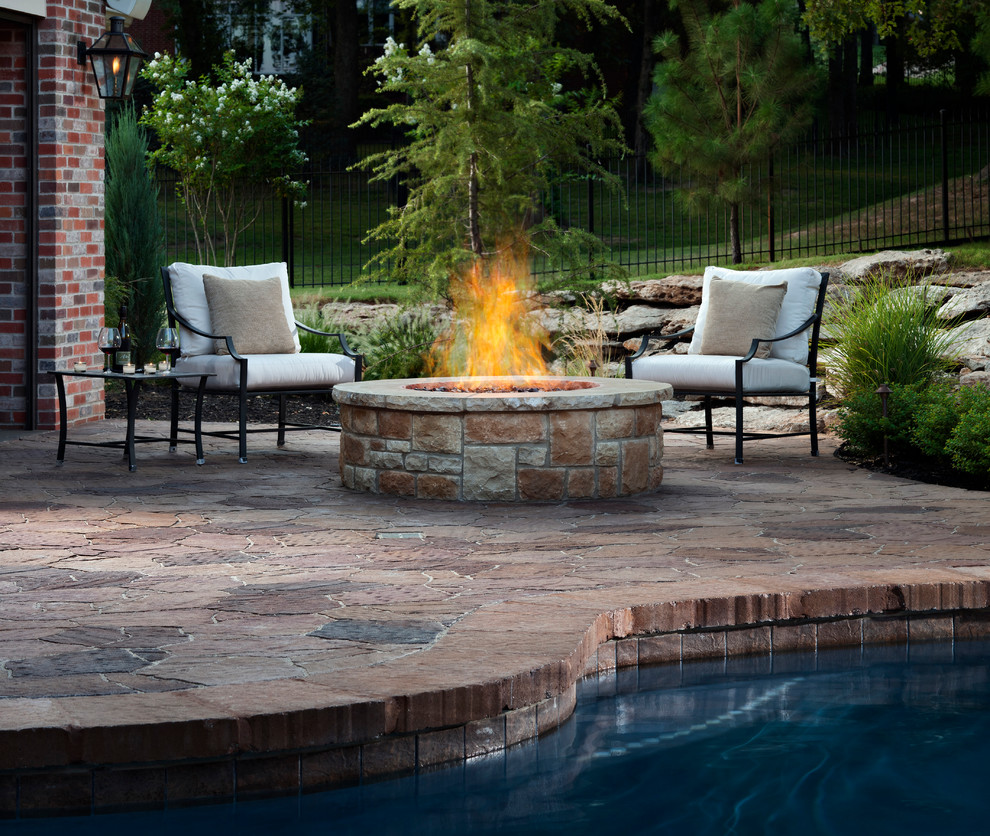 Example of a large mountain style backyard stone patio design in Orange County with a fire pit and no cover
