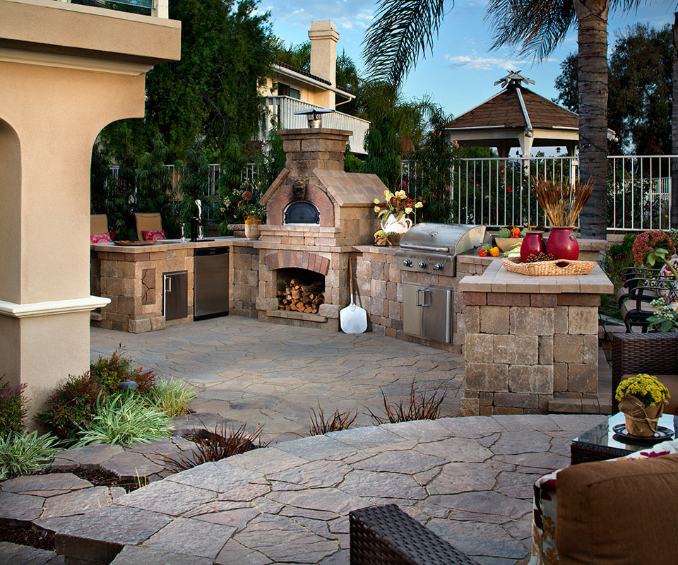 Diseño de patio mediterráneo de tamaño medio sin cubierta en patio trasero con cocina exterior y adoquines de piedra natural