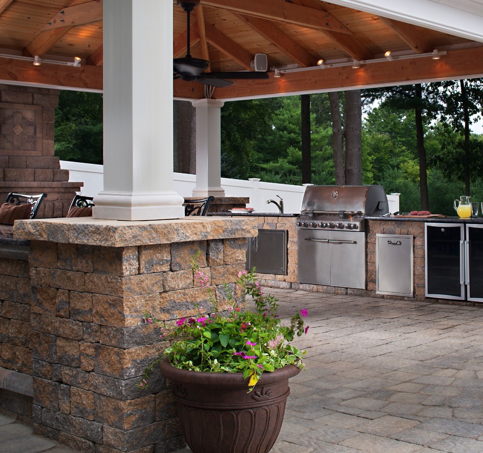 Cette photo montre une terrasse arrière chic de taille moyenne avec une cuisine d'été, des pavés en béton et une extension de toiture.