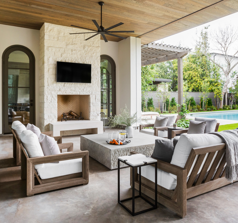 Expansive contemporary back patio in Houston with a roof extension, a fireplace and concrete slabs.