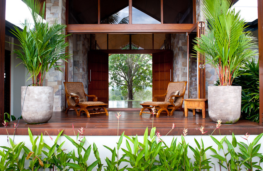 Bild på en mycket stor tropisk uteplats på baksidan av huset, med en fontän, trädäck och takförlängning