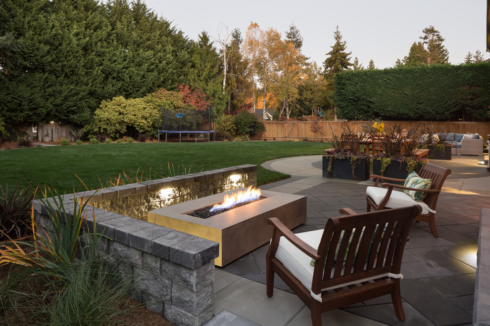 Example of a huge trendy backyard concrete paver patio design in Seattle with a fire pit and no cover