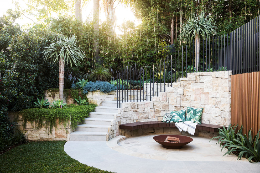 シドニーにある高級なトロピカルスタイルのおしゃれな裏庭のテラス (ファイヤーピット、天然石敷き、日よけなし) の写真