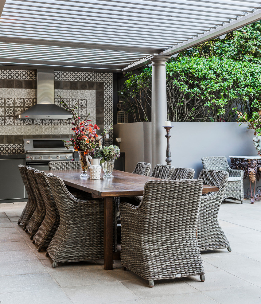 Photo of a large bohemian back patio in Sydney with natural stone paving, a pergola and a bbq area.