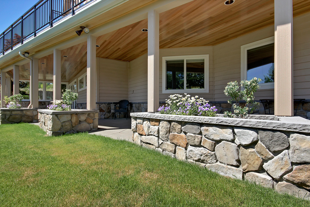Immagine di un grande patio o portico american style dietro casa con un giardino in vaso, lastre di cemento e un tetto a sbalzo