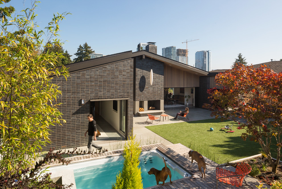 Inspiration pour une grande terrasse arrière vintage avec un foyer extérieur, une dalle de béton et une extension de toiture.