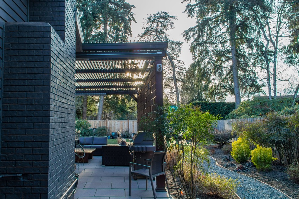 Immagine di un grande patio o portico moderno dietro casa con pavimentazioni in cemento e un tetto a sbalzo