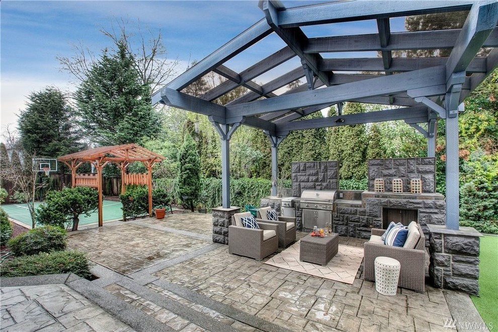 Example of a mid-sized classic backyard stone patio kitchen design in Seattle with a pergola