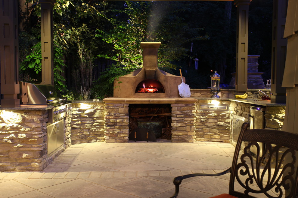 Cette image montre une grande terrasse arrière craftsman avec une cuisine d'été, du carrelage et une pergola.
