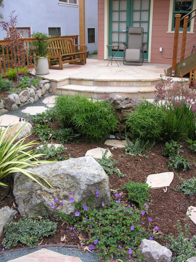 Imagen de patio mediterráneo de tamaño medio sin cubierta en patio trasero con fuente y adoquines de piedra natural
