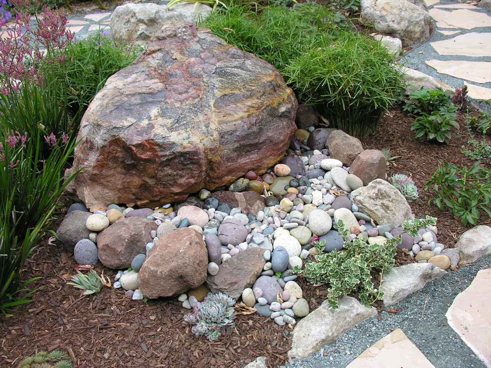 Ejemplo de jardín mediterráneo de tamaño medio en patio trasero con fuente y adoquines de piedra natural