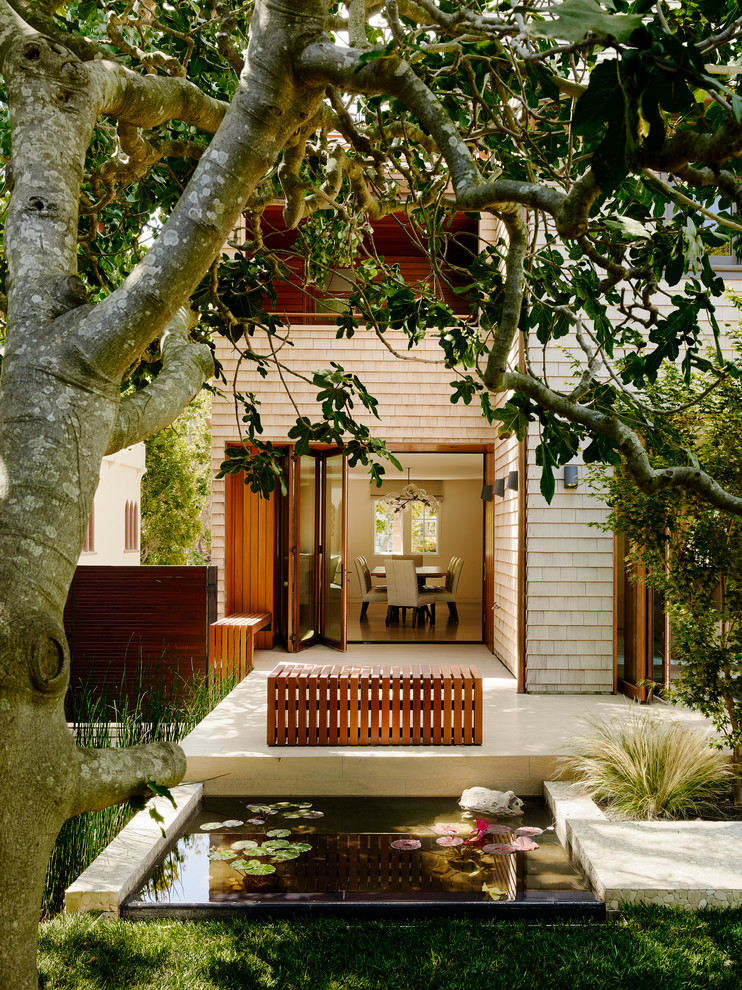 Modelo de patio clásico renovado pequeño en patio trasero con fuente y adoquines de hormigón