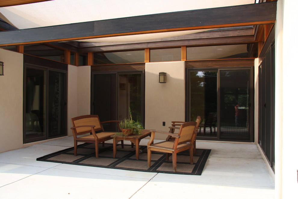 Esempio di un patio o portico contemporaneo di medie dimensioni e dietro casa con lastre di cemento e un parasole