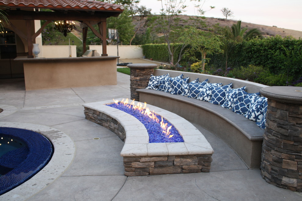 Large tuscan backyard stamped concrete patio photo in Los Angeles with a fire pit and a roof extension