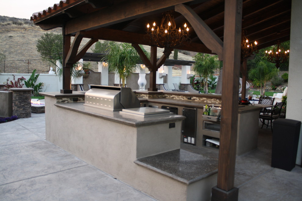 Inspiration for a large mediterranean backyard patio kitchen remodel in Los Angeles with a roof extension