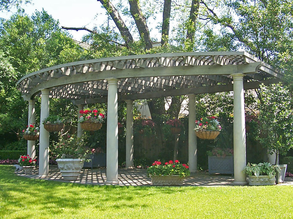Immagine di un patio o portico tradizionale dietro casa con un giardino in vaso, pavimentazioni in pietra naturale e una pergola