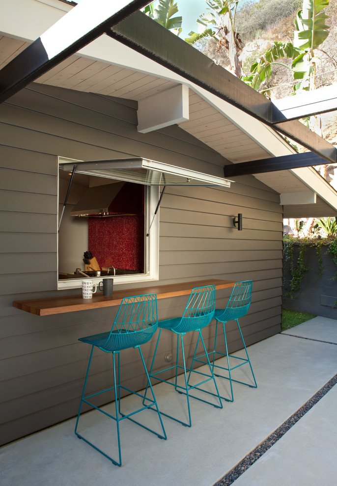 Пример оригинального дизайна: большой двор на заднем дворе в стиле ретро с покрытием из бетонных плит и навесом