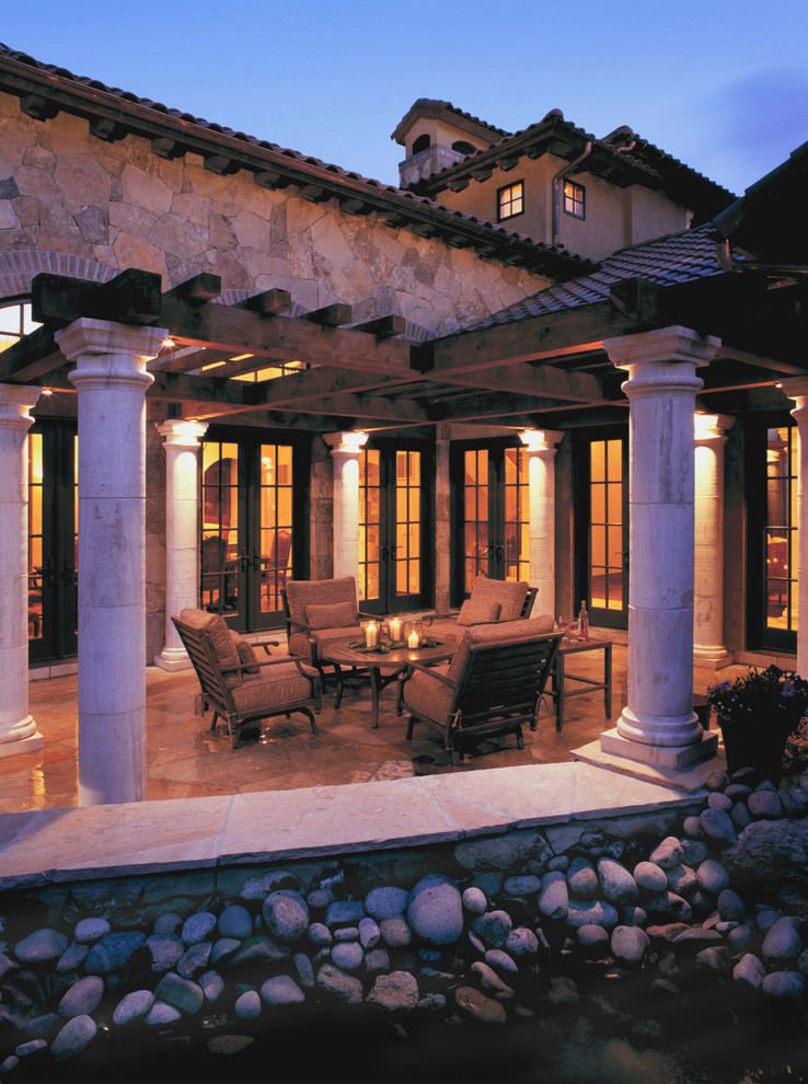 Esempio di un patio o portico mediterraneo con pavimentazioni in pietra naturale e una pergola
