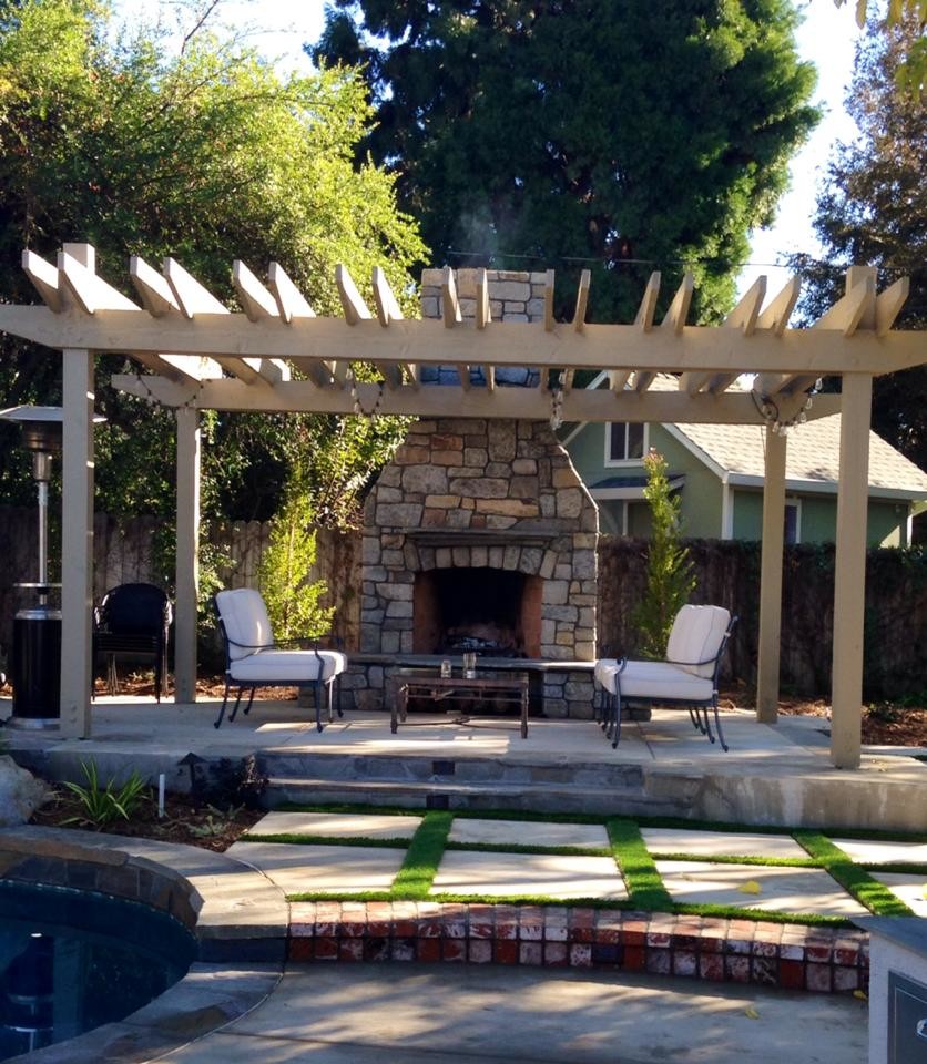 Foto de patio de estilo americano de tamaño medio en patio trasero con chimenea, adoquines de hormigón y pérgola