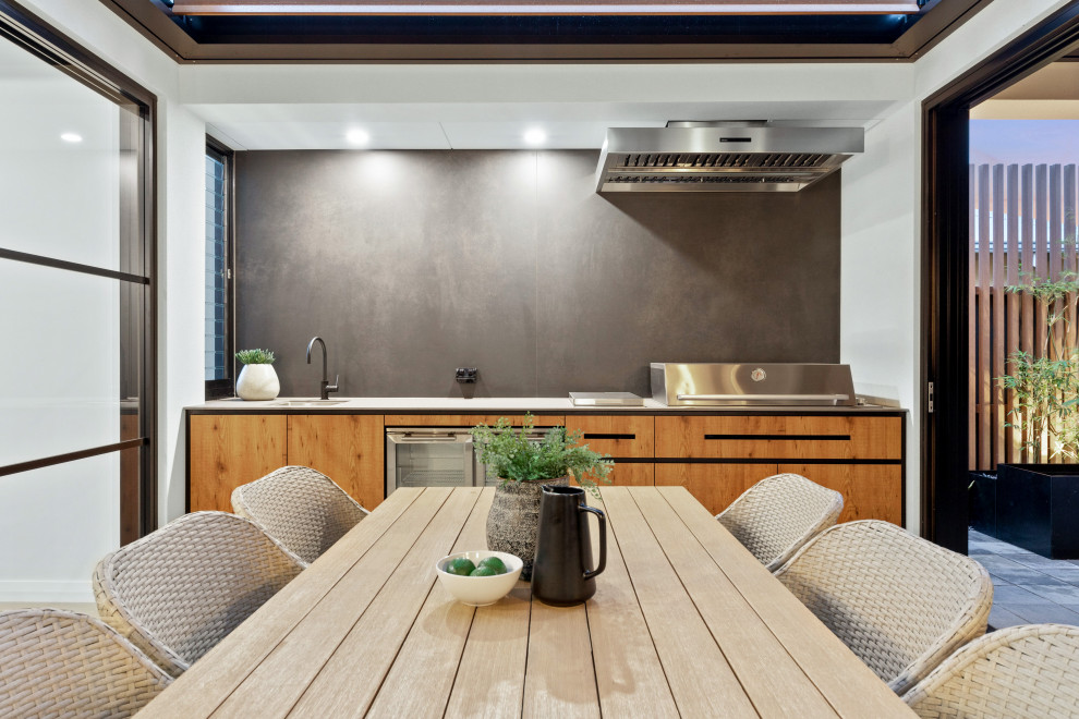 Cette image montre une terrasse design avec une cuisine d'été et une extension de toiture.