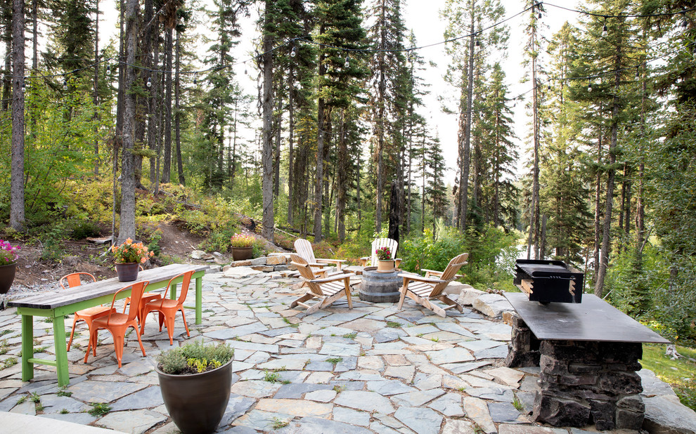 Unbedeckter Rustikaler Patio hinter dem Haus mit Outdoor-Küche und Natursteinplatten in Sonstige