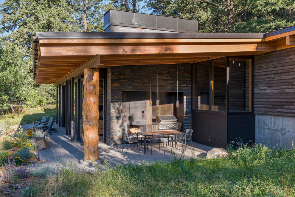 Inspiration pour une terrasse arrière chalet de taille moyenne avec une cuisine d'été, une dalle de béton et une extension de toiture.