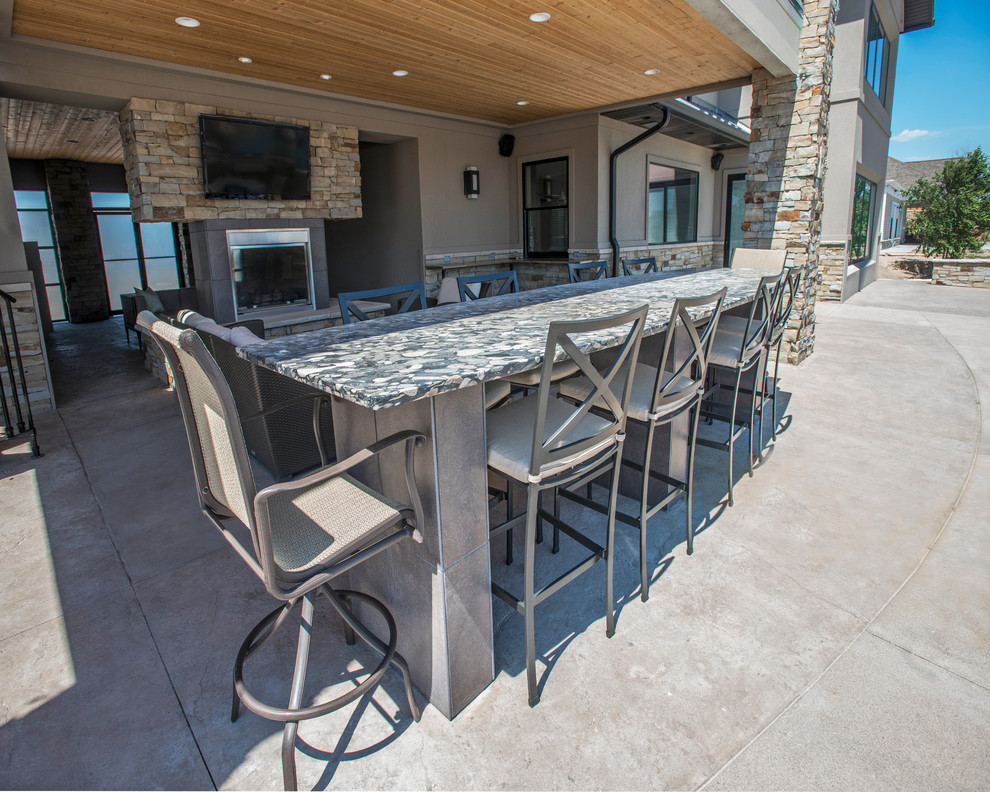Cette image montre une grande terrasse arrière design avec une cuisine d'été, des pavés en pierre naturelle et une extension de toiture.