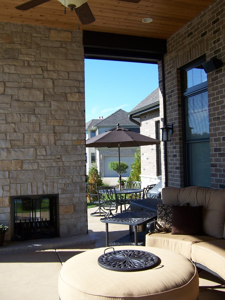 Foto di un patio o portico classico di medie dimensioni e dietro casa con un caminetto, lastre di cemento e un tetto a sbalzo