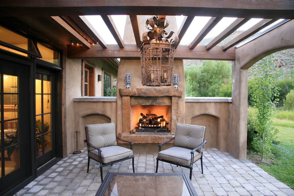 Immagine di un patio o portico stile rurale dietro casa con un focolare e una pergola