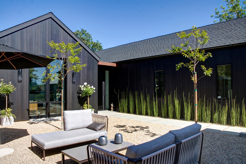 Diseño de patio de estilo de casa de campo sin cubierta en patio trasero con gravilla